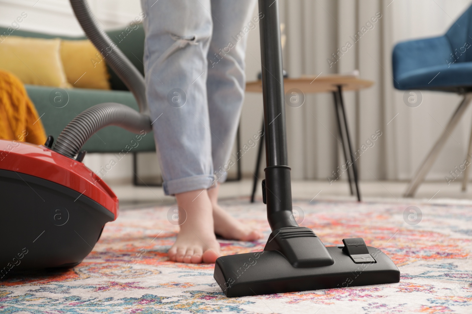 Photo of Woman cleaning carpet with vacuum cleaner at home, closeup