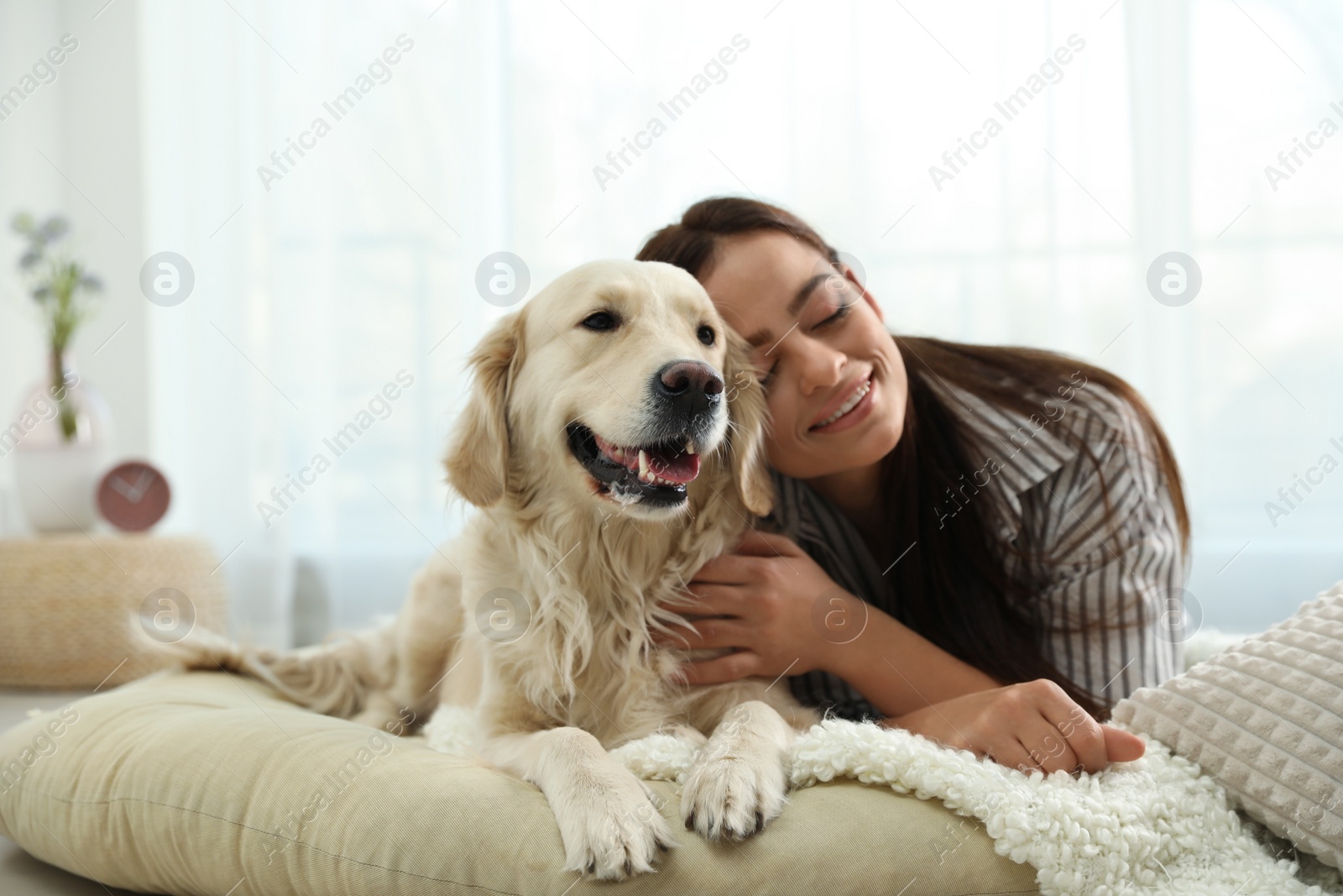 Photo of Young woman and her Golden Retriever at home. Adorable pet