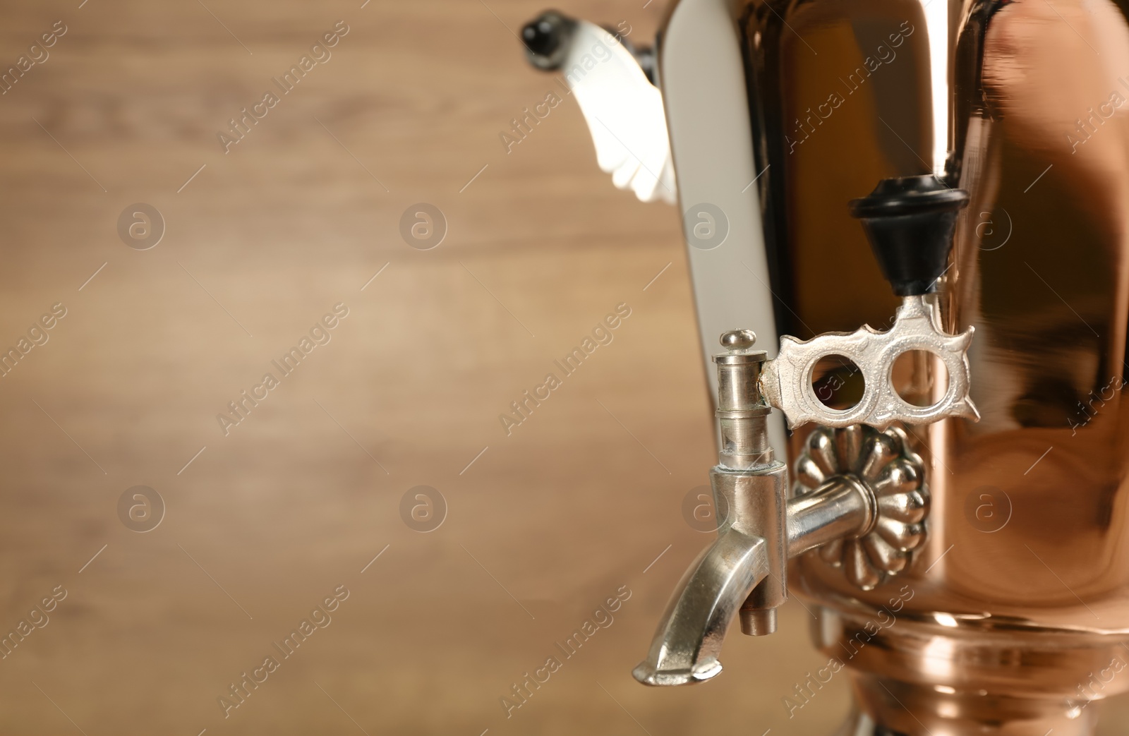 Photo of Closeup view of traditional Russian samovar against wooden background, focus on faucet. Space for text