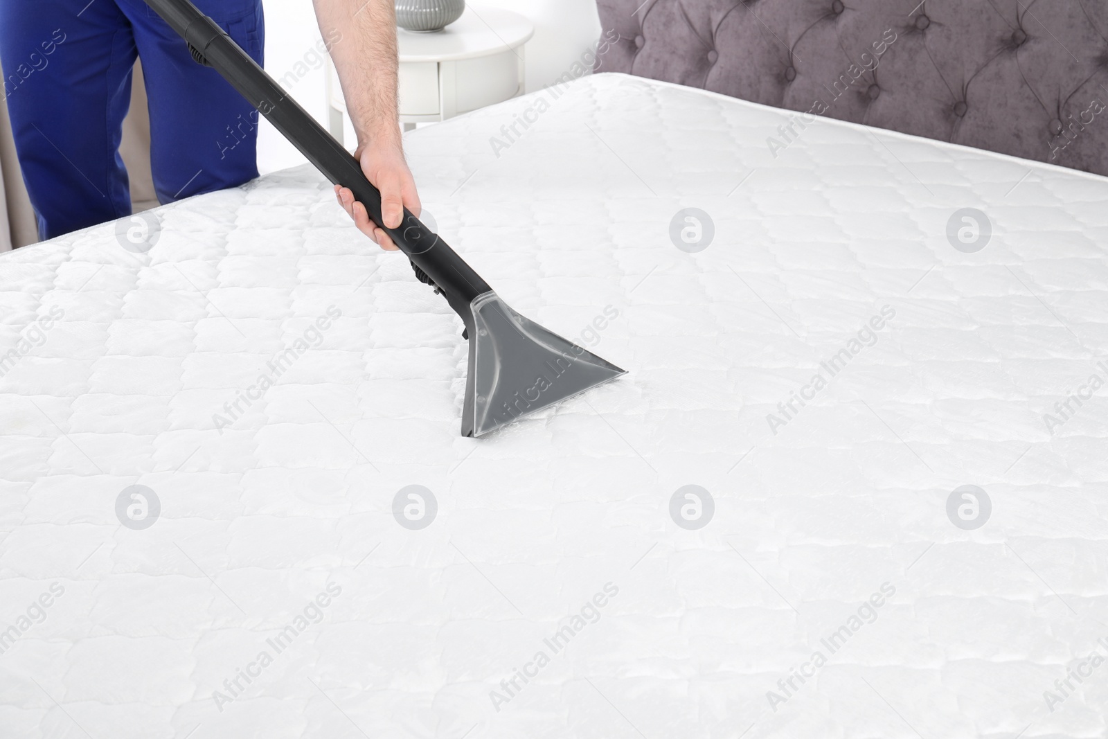 Photo of Man disinfecting mattress with vacuum cleaner, closeup. Space for text