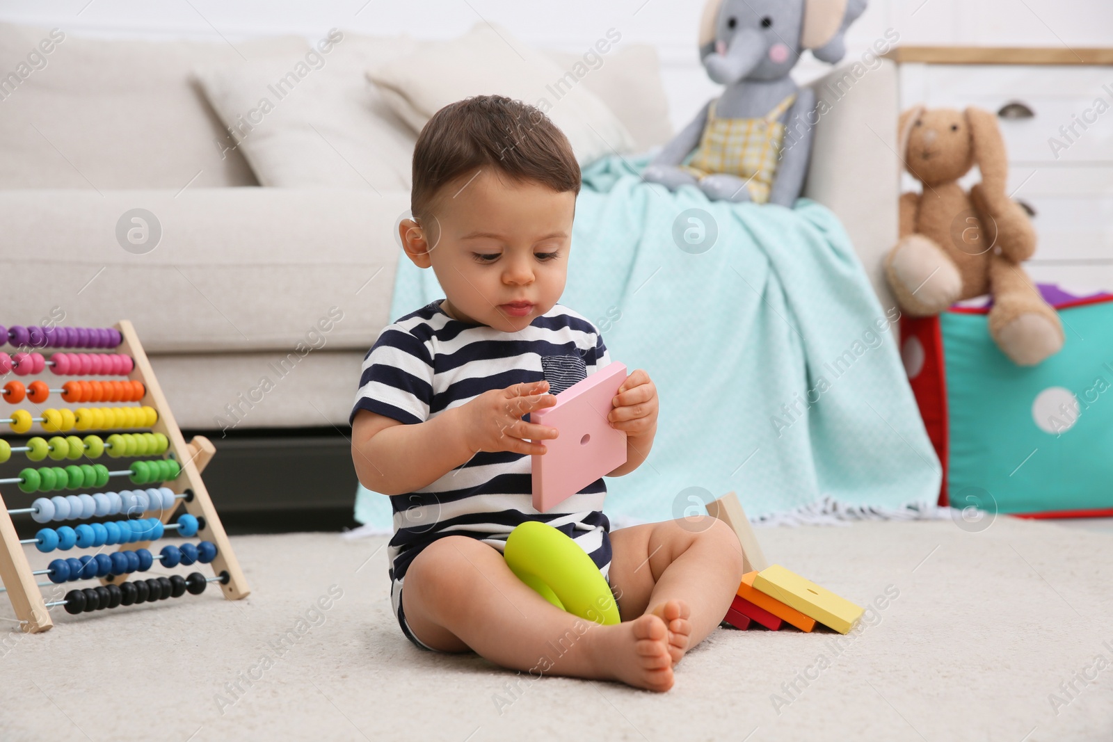 Photo of Cute baby boy playing with toys on floor at home