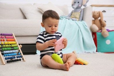 Cute baby boy playing with toys on floor at home