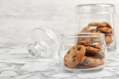 Jar with chocolate chip cookies on marble background, space for text