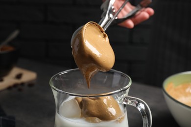 Photo of Woman making dalgona coffee on dark background, closeup