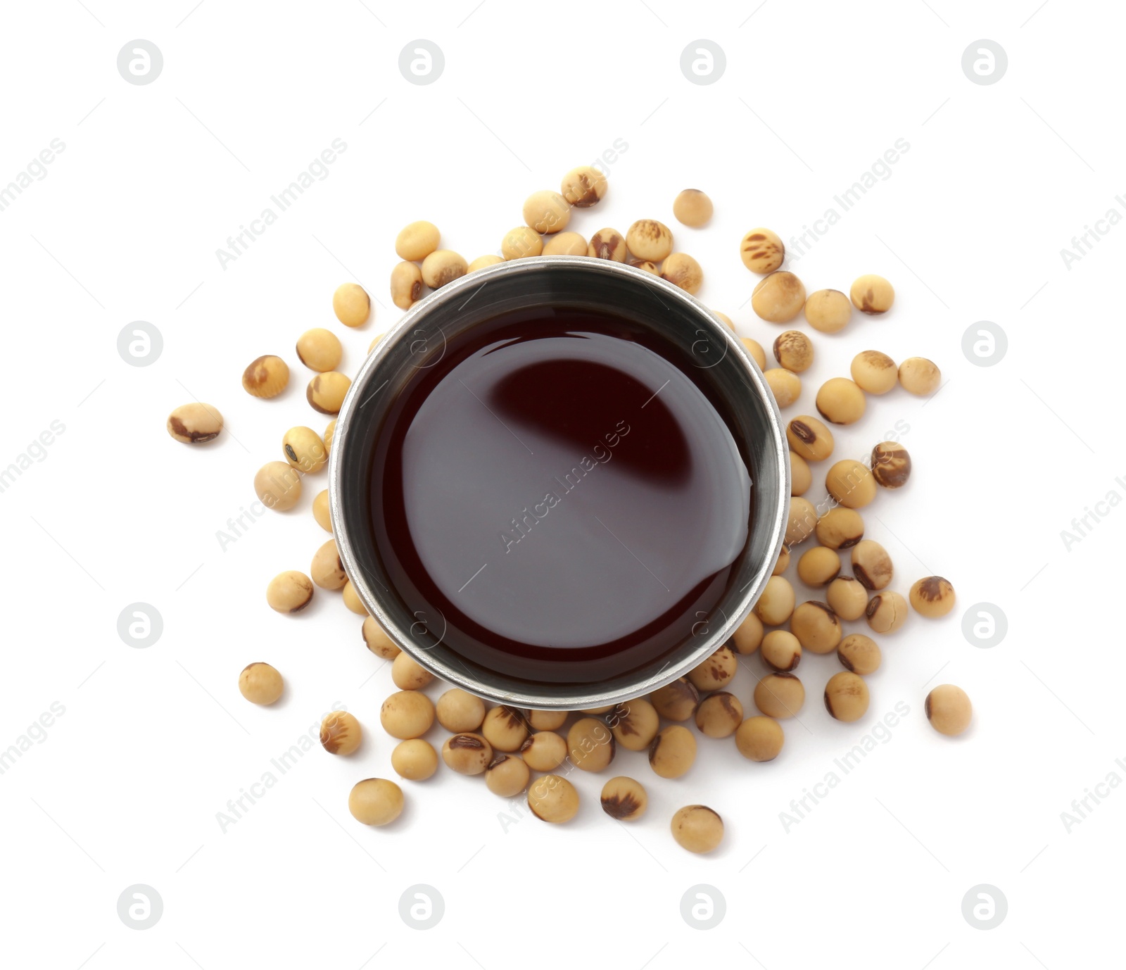 Photo of Tasty soy sauce in bowl and soybeans isolated on white, top view