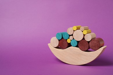 Photo of Wooden balance toy on purple background, space for text. Children's development