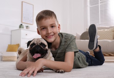 Boy with his cute pug lying on floor in living room
