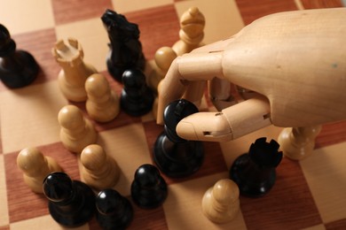 Photo of Robot moving chess piece on board, above view. Wooden hand representing artificial intelligence