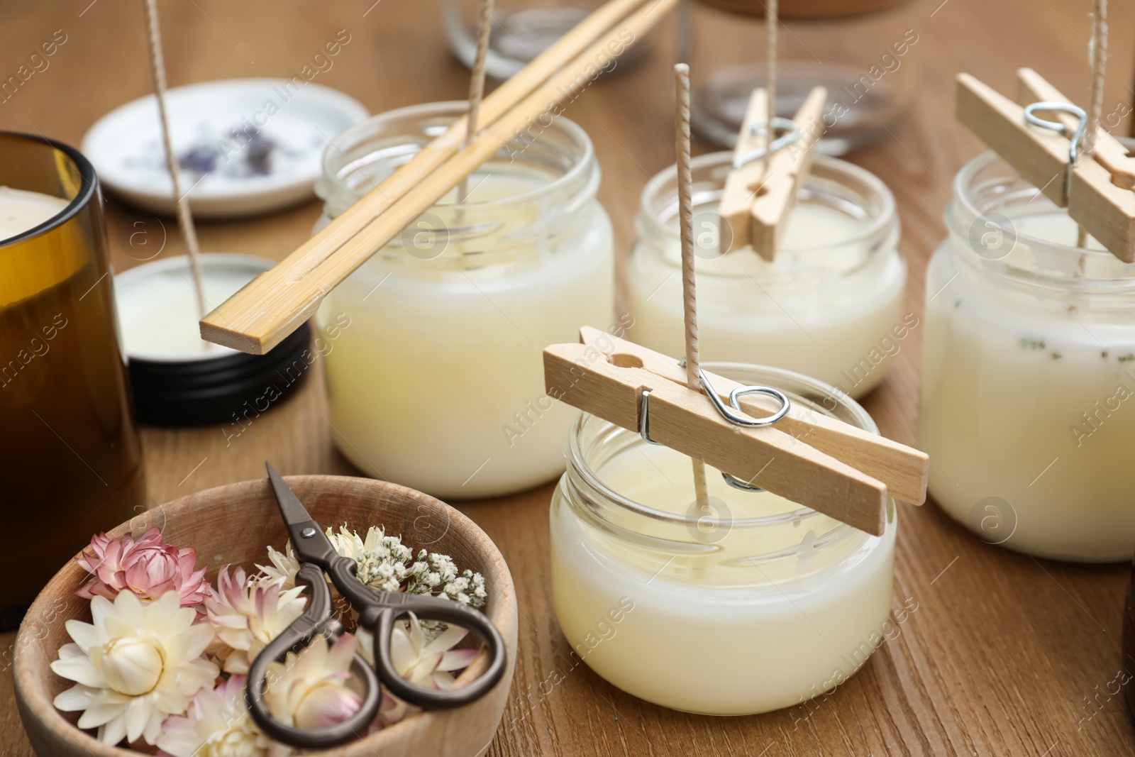 Photo of Glass jars with wax on wooden table. Handmade candles