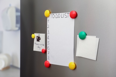 Photo of Paper sheets, to do list and magnets on refrigerator door indoors