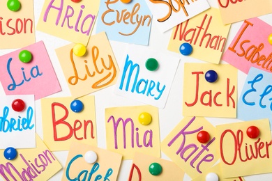 Colorful paper sheets with written different baby names on white background, flat lay