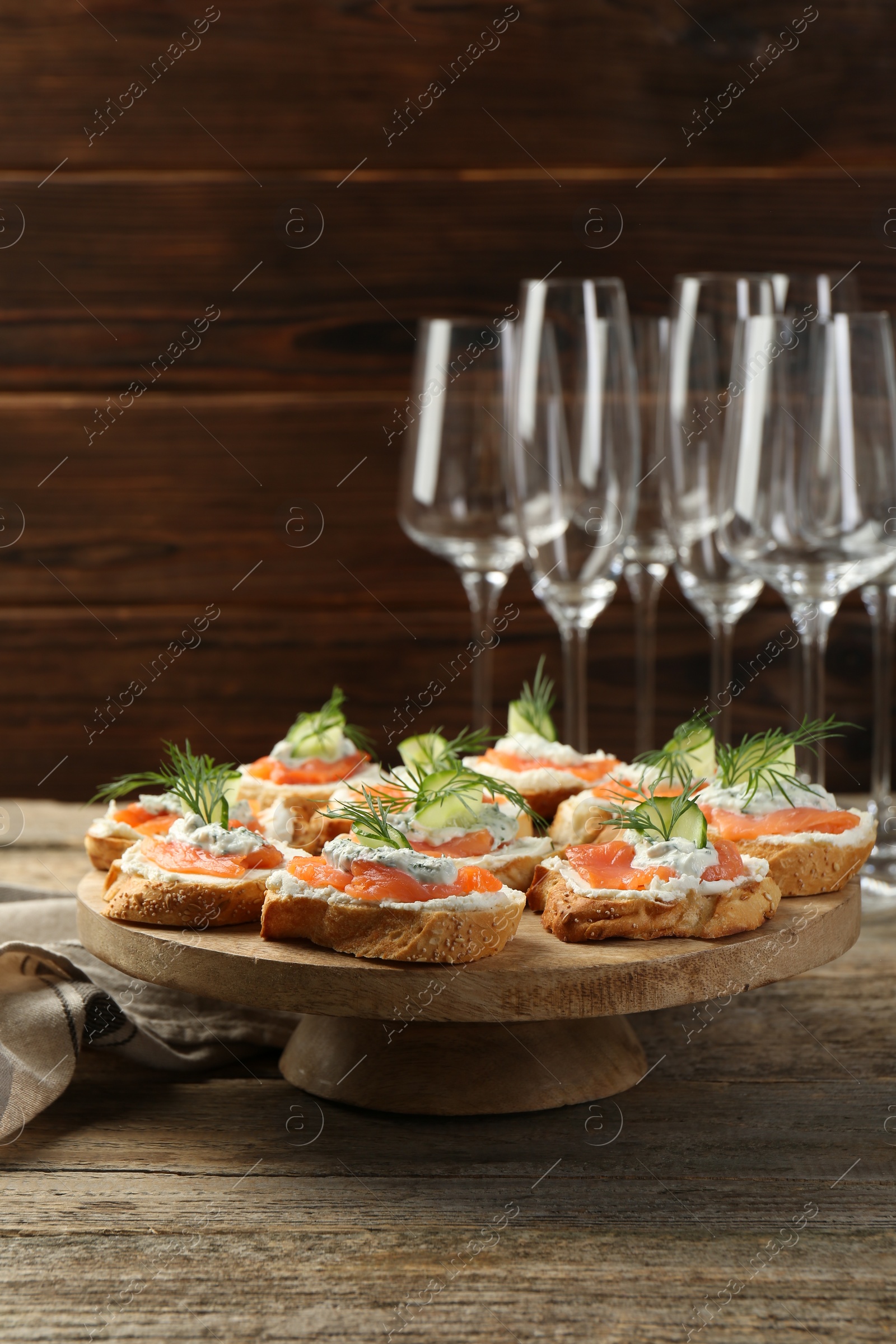 Photo of Tasty canapes with salmon, cucumber, cream cheese and dill on wooden table
