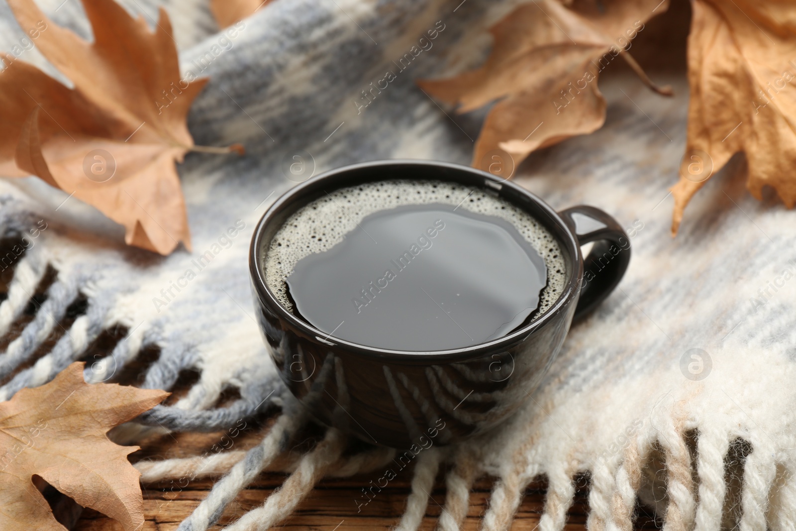 Photo of Composition with hot drink and warm plaid on wooden table, closeup