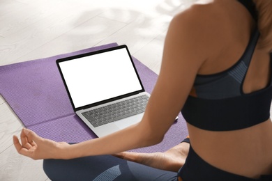 Photo of Woman having online video class via laptop at home, closeup. Distance yoga course during coronavirus pandemic