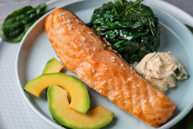 Photo of Tasty salmon with spinach and avocado on plate, closeup