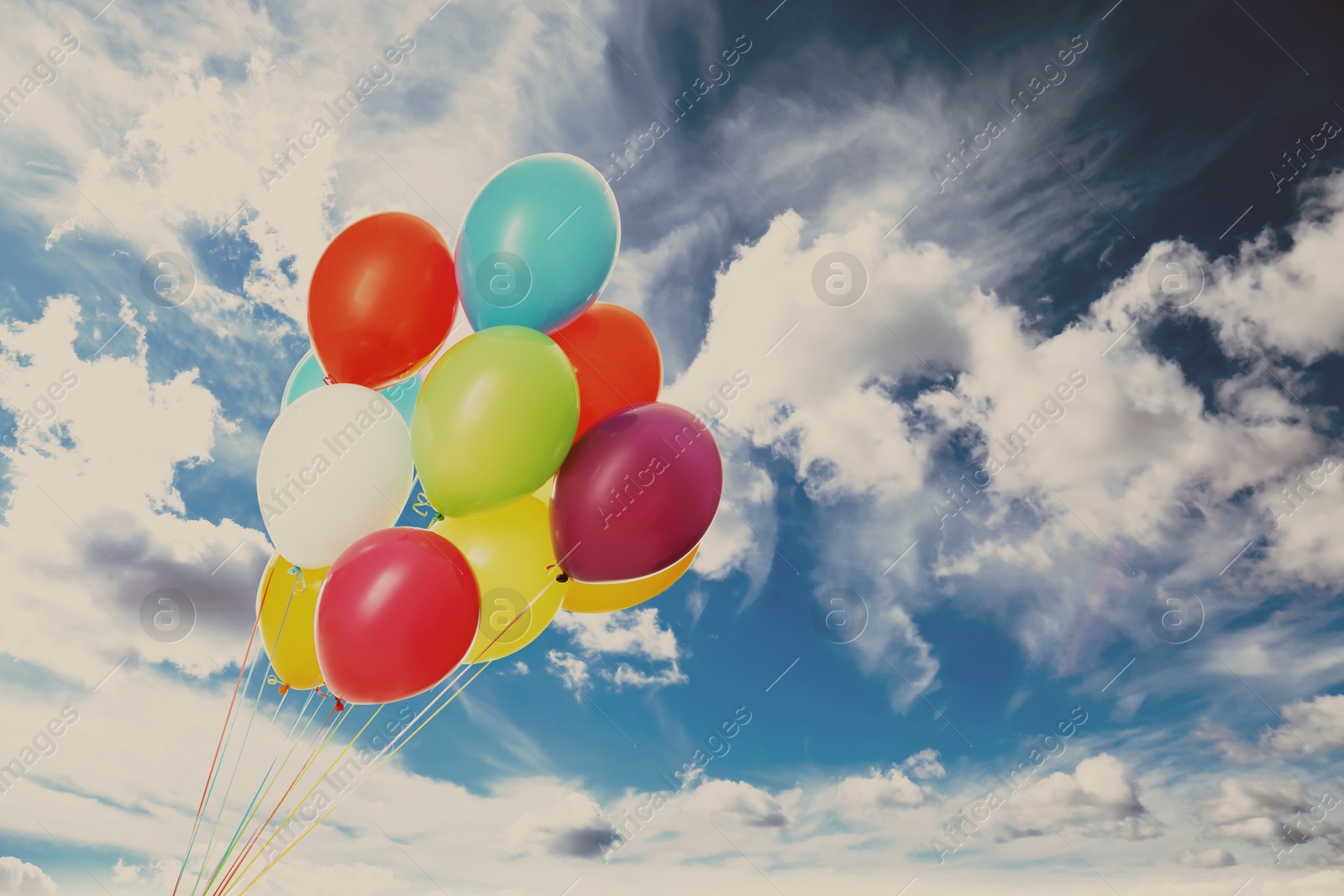 Image of Colorful balloons flying in blue sky with clouds. Space for text