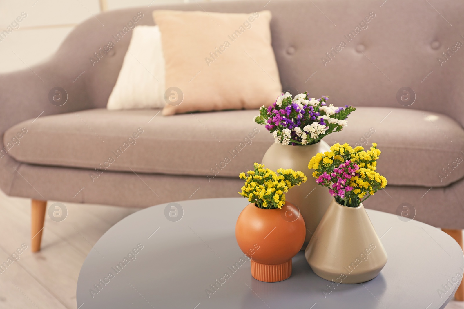 Photo of Beautiful flowers in vases as element of interior design on table. Space for text