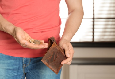Photo of Man putting coins into wallet indoors, closeup. Space for text