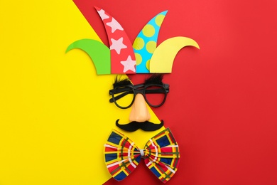Photo of Flat lay composition clown's face made of party glasses, hat and bow tie on color background