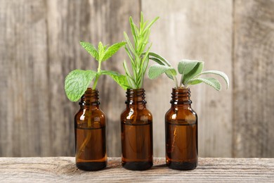 Bottles with essential oils and herbs on wooden table