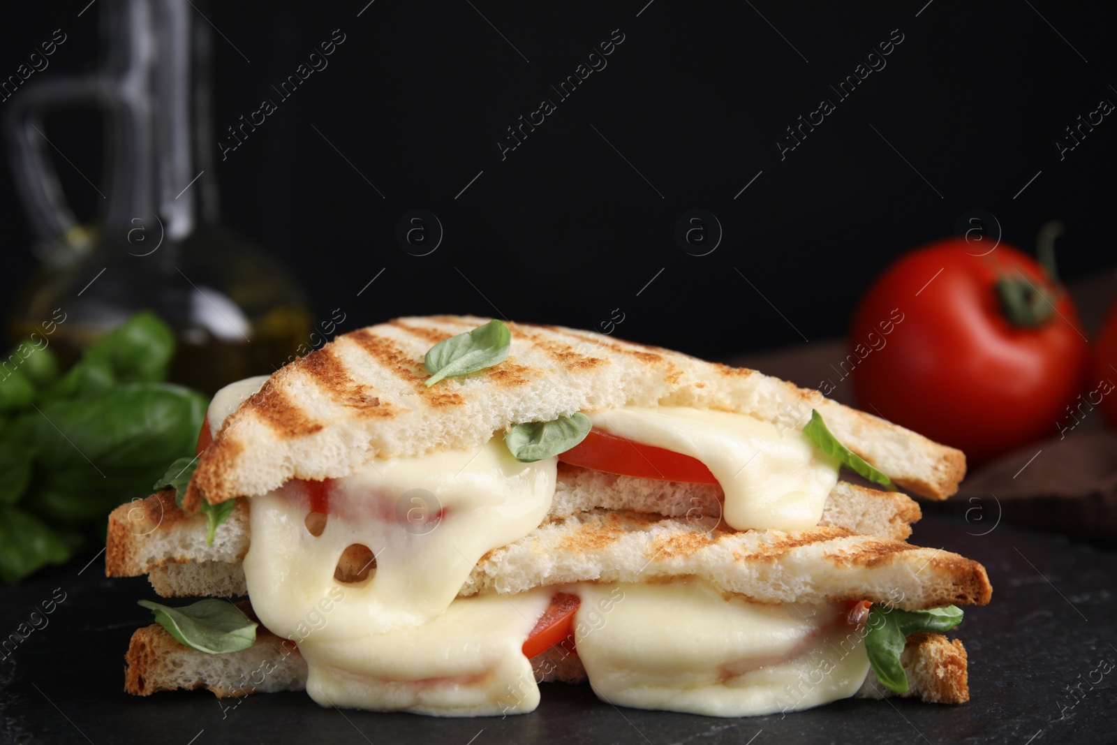 Photo of Delicious grilled sandwiches with mozzarella, tomatoes and basil on black board. Space for text