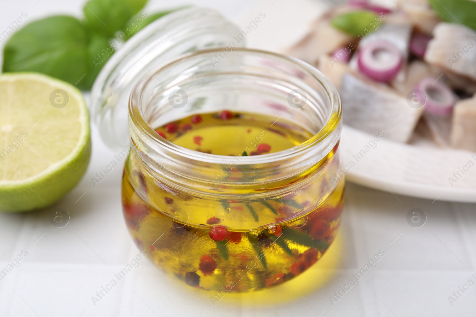 Photo of Tasty fish marinade in jar on light tiled table, closeup