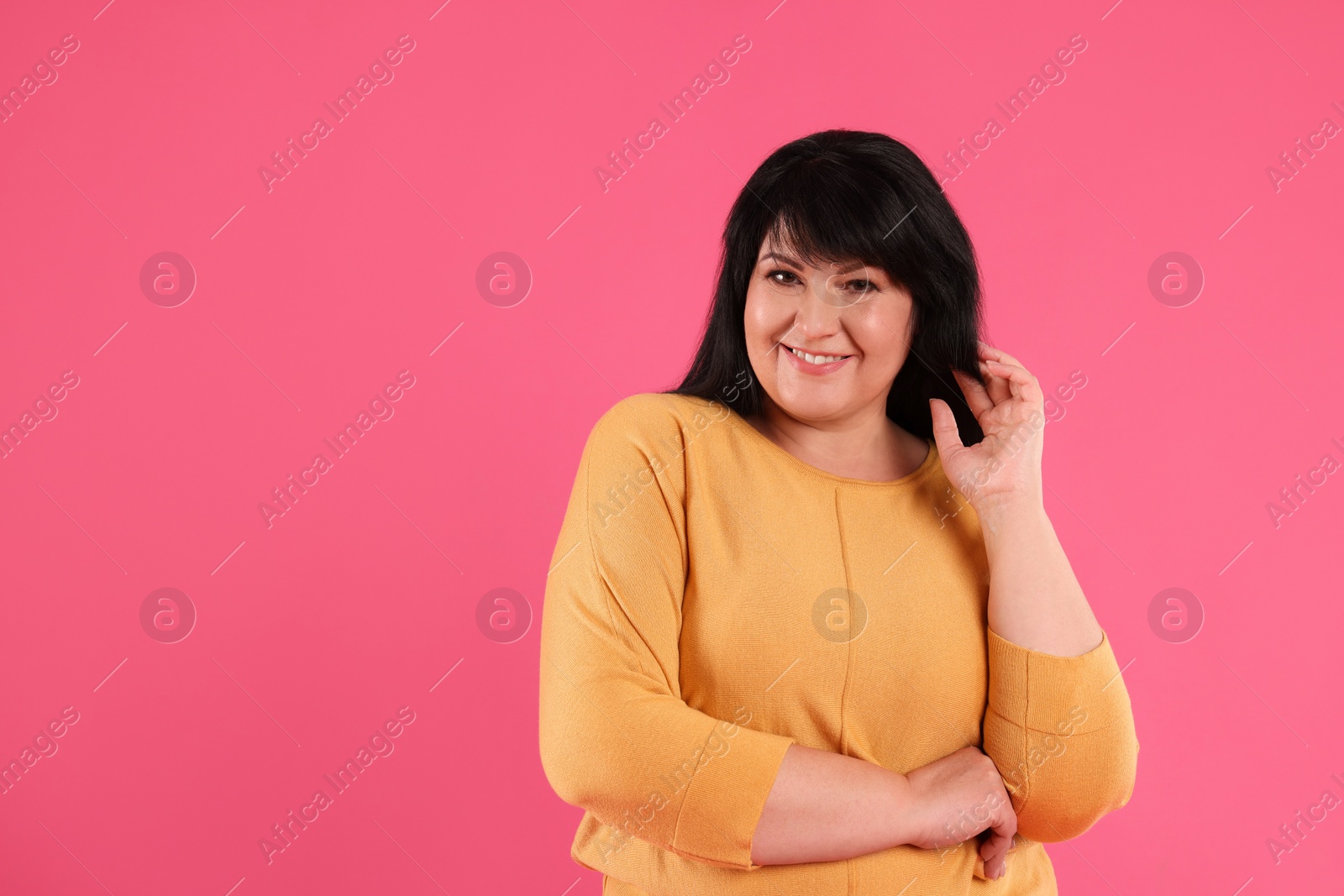 Photo of Beautiful overweight mature woman with charming smile on pink background. Space for text