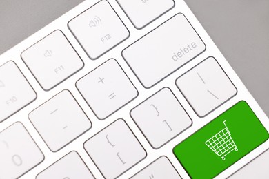 Image of Internet store. Green button with shopping cart on computer keyboard, top view