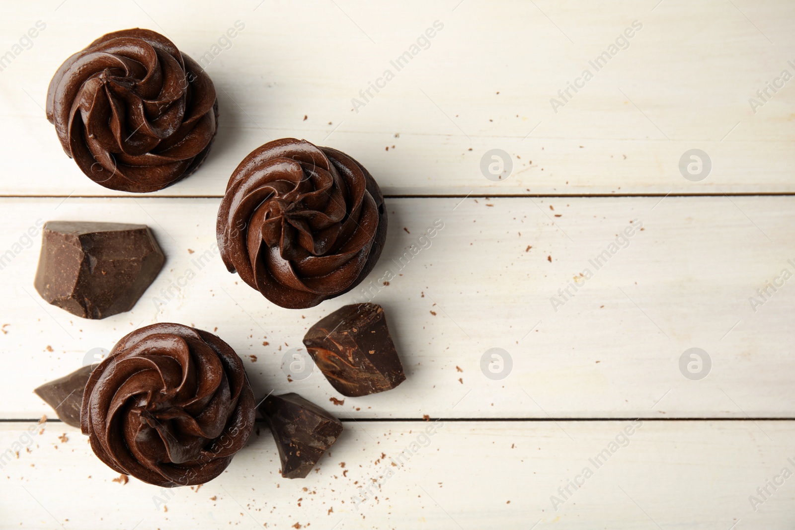 Photo of Flat lay composition with delicious chocolate cupcakes on white wooden table. Space for text