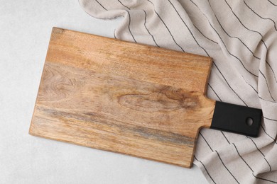 Photo of One wooden cutting board and tablecloth on light grey table, top view. Cooking utensil