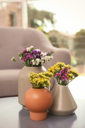 Photo of Beautiful flowers in vases on table. Element of interior design