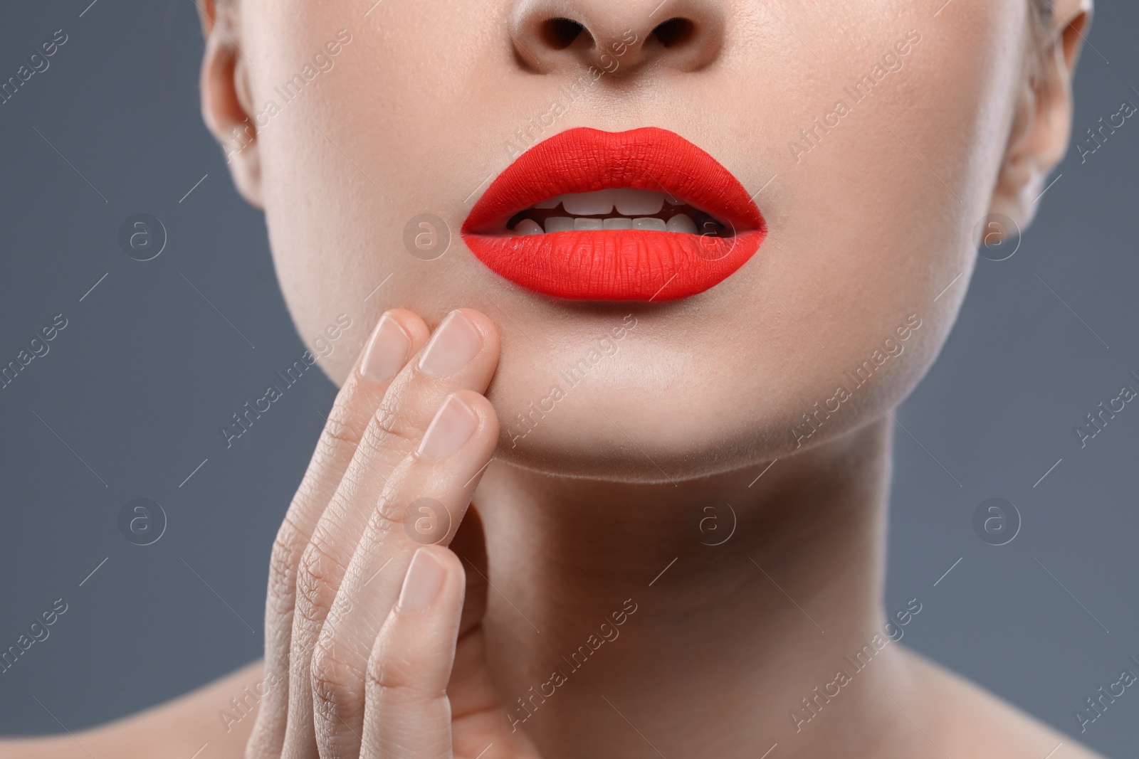 Photo of Young woman with beautiful red lips on grey background, closeup