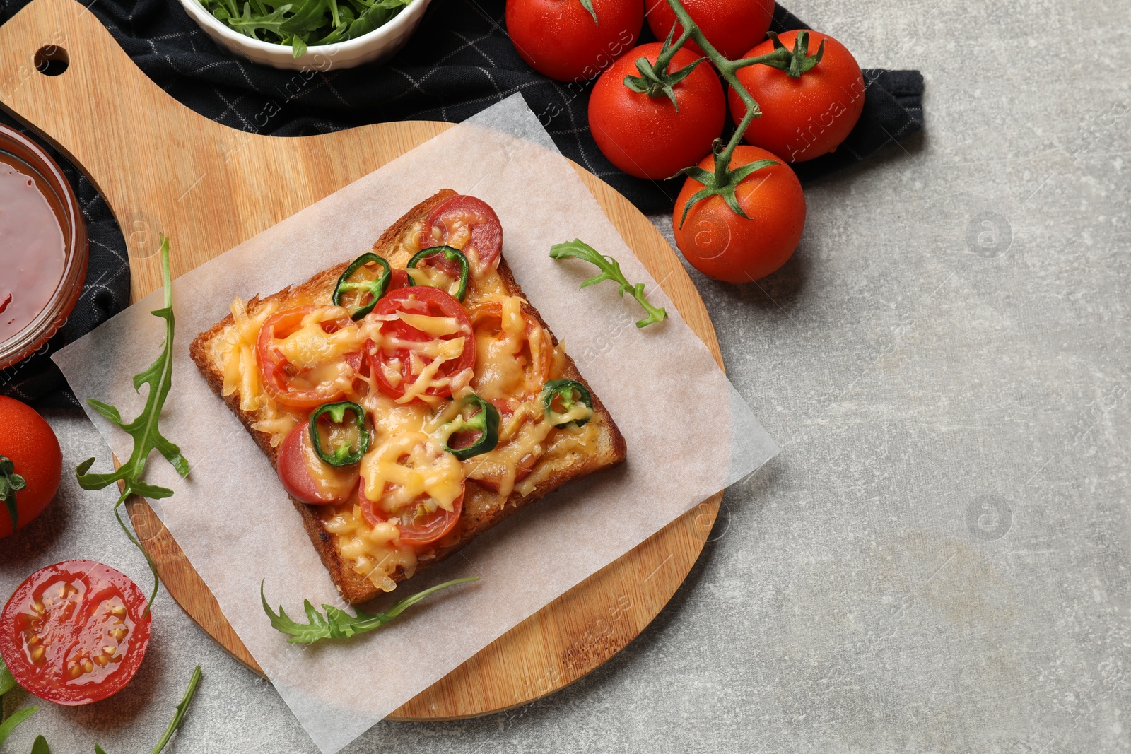 Photo of Tasty pizza toast, sauce, tomatoes and arugula on grey table, top view. Space for text