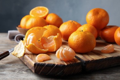 Photo of Board with ripe tangerines on wooden table