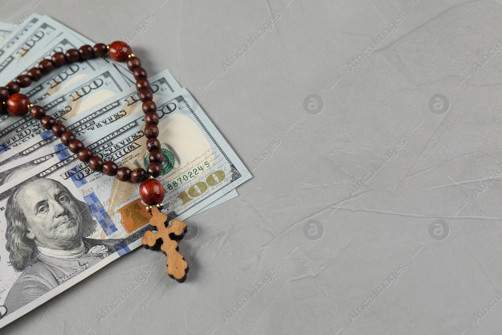 Photo of Wooden cross and money on grey table. Space for text
