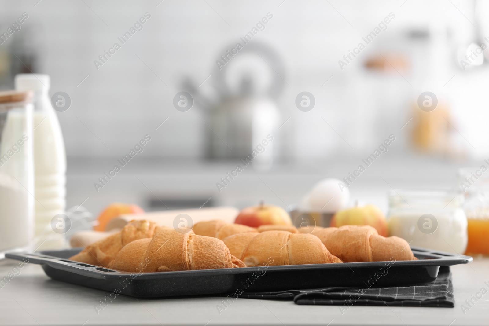 Photo of Baking tray with delicious croissants on kitchen table