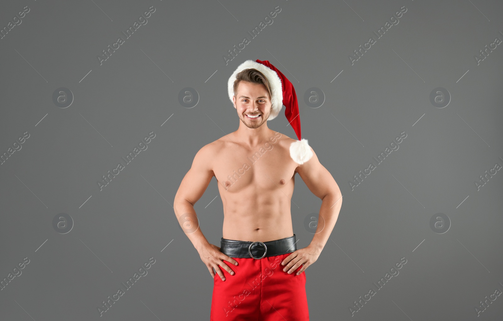 Photo of Shirtless young Santa Claus with sexy body on color background