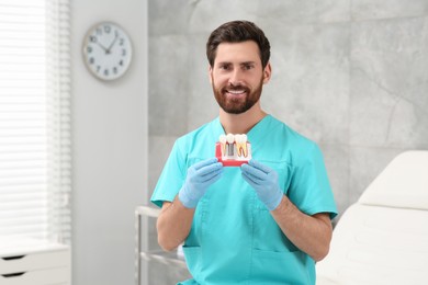 Dentist holding educational model of dental implant in clinic