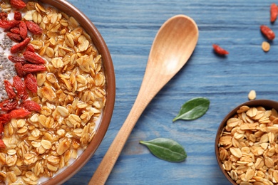 Smoothie bowl with goji berries and spoon on blue wooden table, closeup