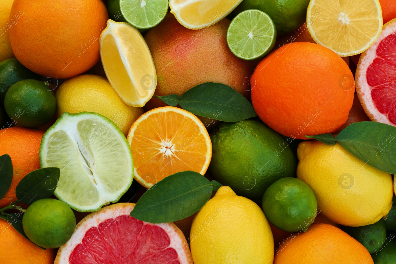 Photo of Different fresh citrus fruits and leaves as background, top view.