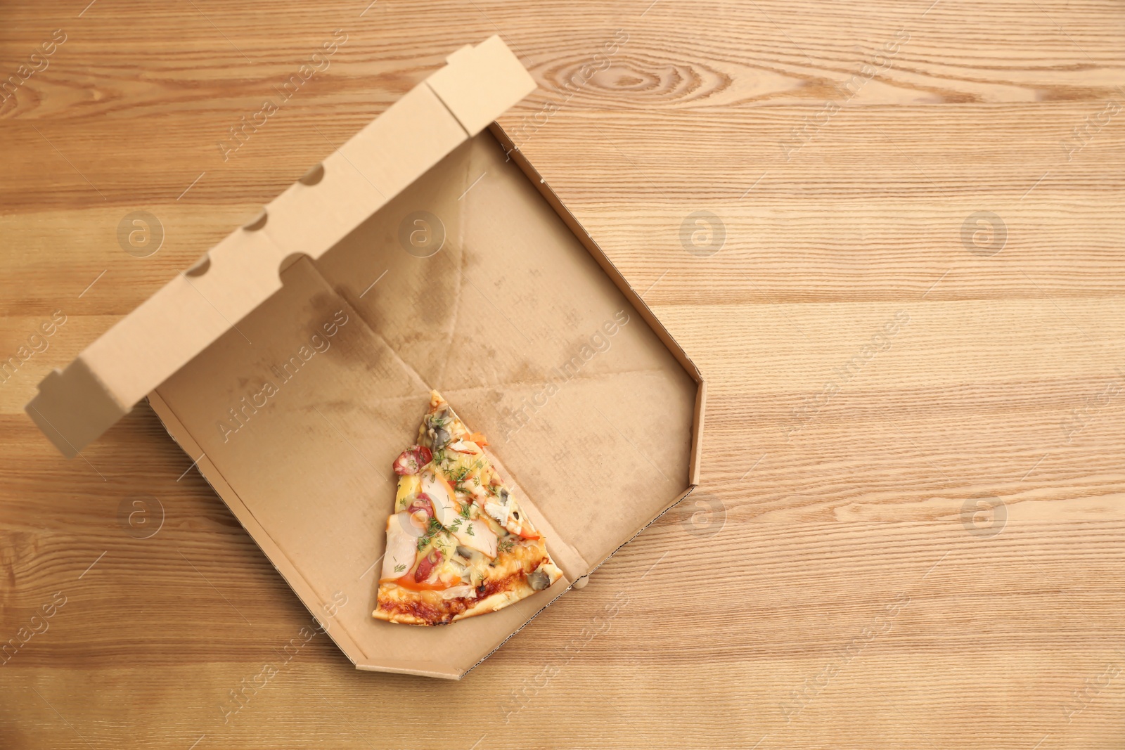 Photo of Cardboard box with pizza piece on wooden background, top view with space for text
