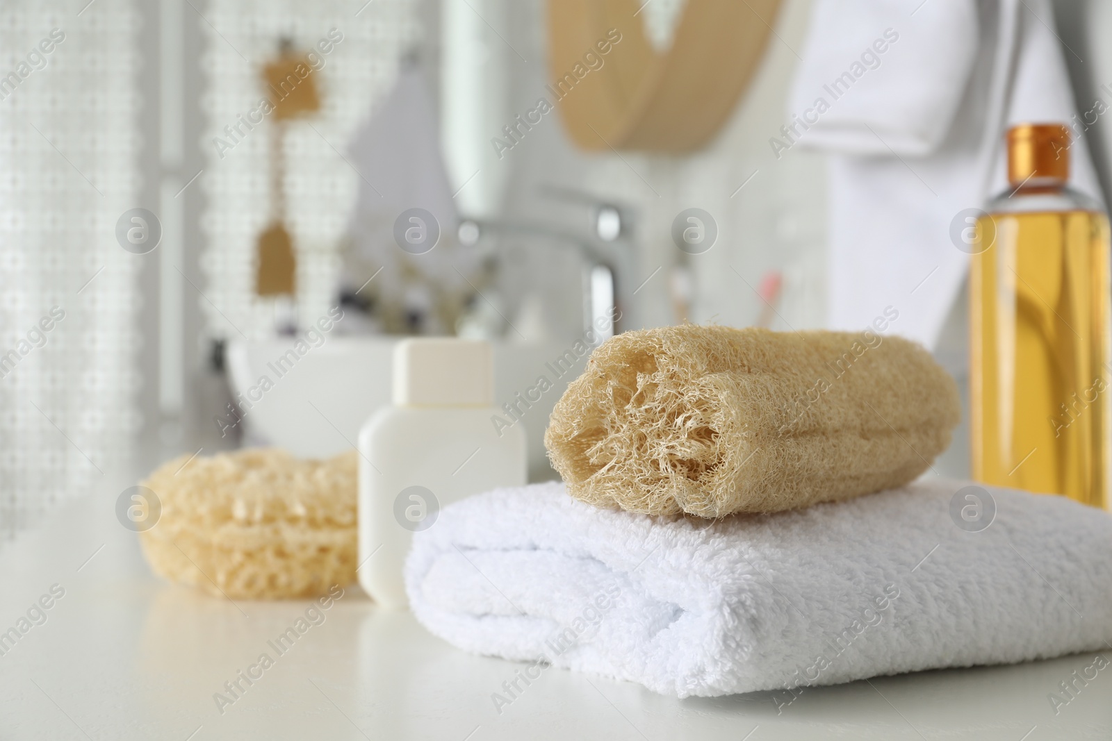 Photo of Natural loofah sponge and towel on table in bathroom. Space for text