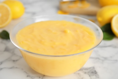 Photo of Delicious lemon curd on white marble table, closeup