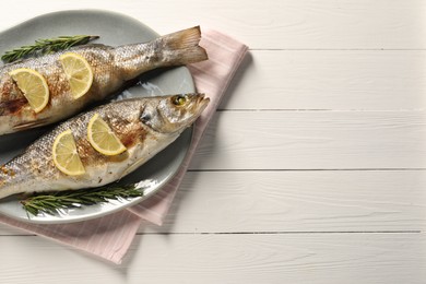 Photo of Delicious baked fish, lemon and rosemary on white wooden table, top view. Space for text