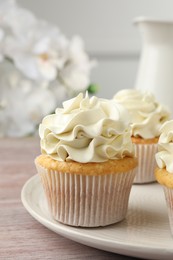 Photo of Tasty cupcakes with vanilla cream on pink wooden table, closeup