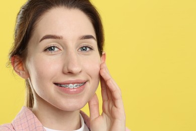 Photo of Portrait of smiling woman with dental braces on yellow background. Space for text