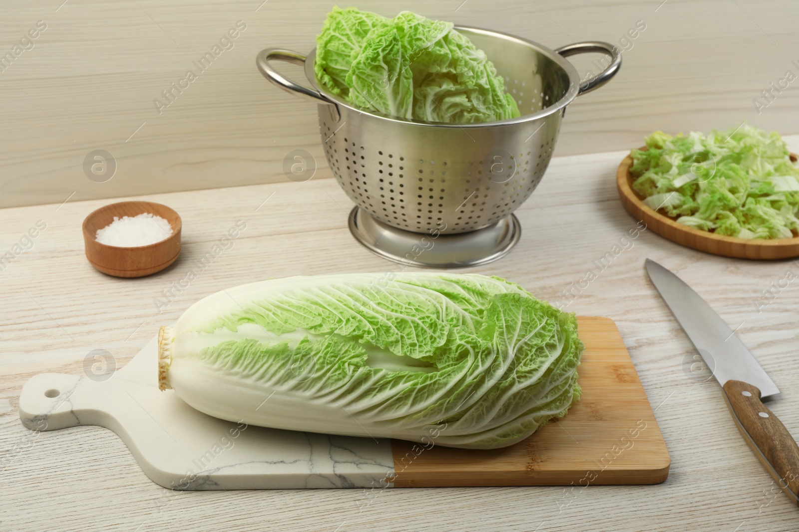 Photo of Fresh ripe Chinese cabbage and knife on white wooden kitchen table