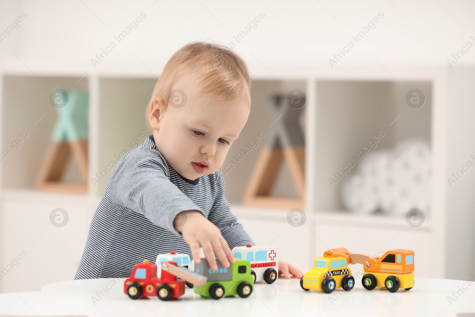 Photo of Children toys. Cute little boy playing with toy cars at white table in room, space for text