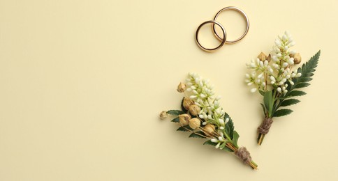 Photo of Small stylish boutonnieres and rings on beige background, flat lay. Space for text