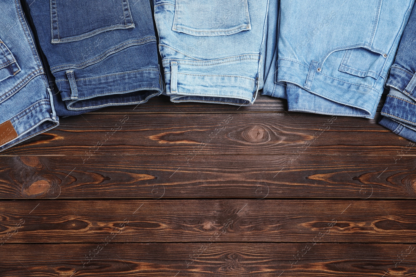 Photo of Collection of stylish jeans on wooden background, flat lay. Space for text